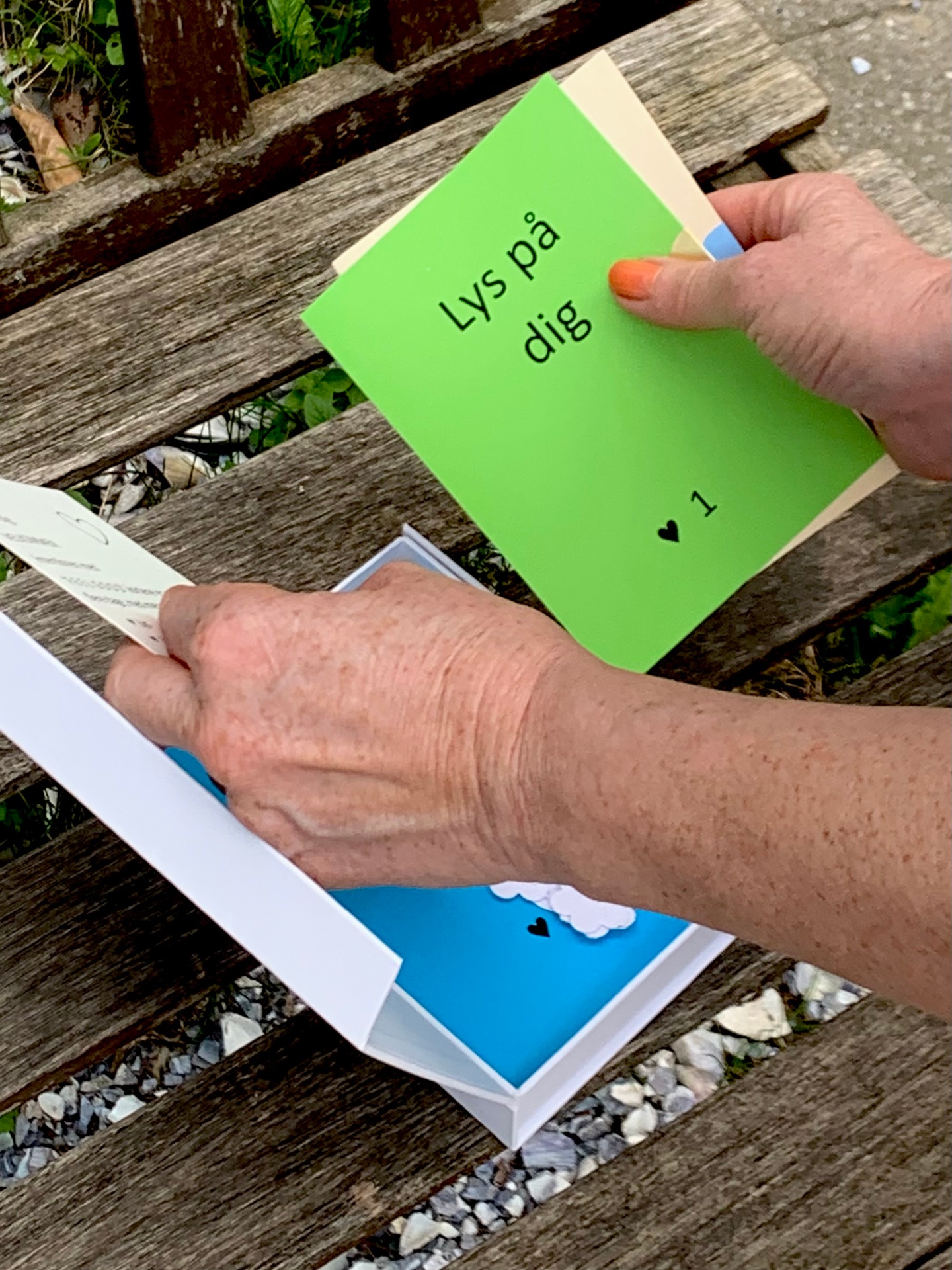A woman holding a Feel Good Card by the window
